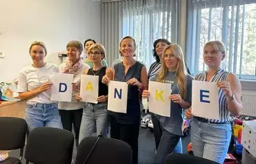 Valeria Kaiser (center) and the staff of the Matusya center in Vienna hold up letter signs spelling out the word 'DANKE' to thank donors in the summer of 2023. [Valeria Kaiser personal archive]