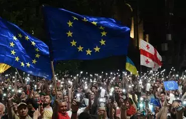 Demonstrators in Tbilisi wave EU and Georgian flags in support of Georgia's candidacy for European Union membership on June 24, 2022, a day after the bloc's leaders, seeking widespread political reforms in Georgia, deferred its candidacy. [Vano Shlamov/AFP]