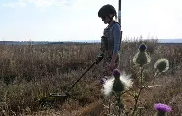 A deminer of the 'Demining of Ukraine' charity uses a metal detector to search for mines in a field near the town of Derhachi, Kharkiv province, on October 1. [Sergey Bobok/AFP]