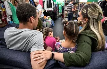 Yulia (right) and Alexander (left) with their children, who fled the town of Kupiansk in northeastern Ukraine, sit at a humanitarian aid warehouse of the Lighthouse Charity Foundation (Mayak Fund) in Moscow on August 9. [Alexander Nemenov/AFP]