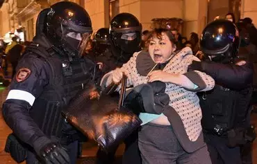 Police officers detain a woman in Moscow on September 21, 2022, following calls to protest against the 'partial mobilisation' announced by President Vladimir Putin. [Alexander Nemenov /AFP]