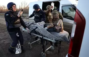 Policemen hand over a wounded man to employees of Ukrainian Emergency Service on a road outside in Avdiivka, Donetsk province, on November 13, amid the Russian invasion in Ukraine. [Anatolii Stepanov/AFP]