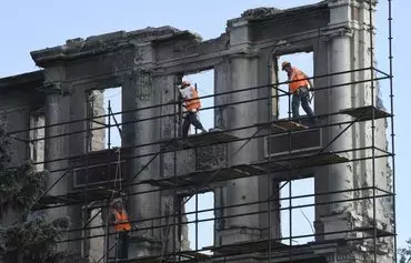 Construction workers restore a destroyed building in Mariupol, Ukraine, on August 16. [AFP]