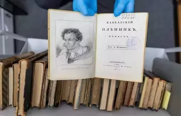 A university employee presents a forged copy of the 1822 work 'Kavkazskiy plennik: povest' by Alexander Pushkin at the University of Warsaw library in Warsaw, Poland, on November 14. [Wojtek Radwanski/AFP]