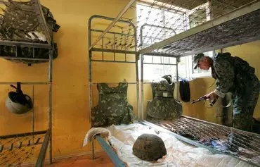 A Russian soldier examines an abandoned Georgian army barracks 95km east of Sukhumi in the town of Ptysh on August 18, 2008, in the breakaway Abkhazia region. [Viktor Drachev/AFP]