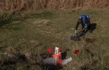 An ecological investigator November 7 collects soil in the area that was flooded following the Kakhovka dam explosion, for a war crime investigation into allegations of Russian ecocide, in Chornobaivka village, outskirts of Kherson. [Roman Pilipey/AFP]