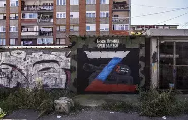 This photograph taken on September 19, 2022, shows a mural reading 'Serbs for Russians, for freedom, for victory' and depicting a tank with the letter 'Z,' the tactical insignia of Russian troops in Ukraine, in northern Mitrovica, Kosovo, where an ethnic Serb majority lives. In the deeply divided city of Mitrovica, the fighting in Ukraine has added another layer of separation between northern Kosovo's Serbs and ethnic Albanians and has stirred bitter memories of their own past war. [Armend Nimani/AFP]