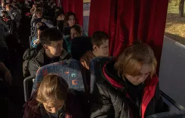 Children ride on a bus during their evacuation to western Ukraine, from the southern city of Kherson, on October 30, amid the Russian invasion of Ukraine. [Roman Pilipey/AFP]