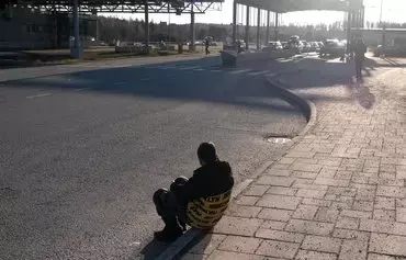 An asylum seeker sits on the ground near the Nuijamaa border crossing between Finland and Russia, in Lappeenranta, Finland, on November 17. The Finnish government announced the three-month closure of four of its eight border crossings with Russia starting November 18. All eight border points are now closed until at least December 13. [Alessandro Rampazzo/AFP]