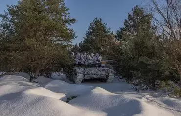 Ukrainian servicemen sitting on a tank take part in military training that focuses on fighting sabotage groups in Chernihiv province on December 5, amid the Russian invasion of Ukraine. [Roman Pilipey/AFP]