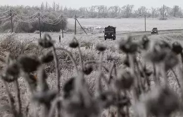 Украинские военные машины проезжают мимо поля обледеневших подсолнухов. Донецкая область, 12 декабря. [Анатолий Степанов/AFP]