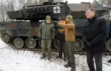 Lithuanian Defense Minister Arvydas Anusauskas (left) attends the testing of a Leopard 2 tank at the Gaiziunai military training area near the Rukla military base in Lithuania,on December 15. The tank was brought from combat in Ukraine and was repaired in Lithuania. [Petras Malukas/AFP]