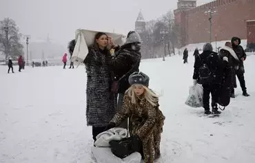 Женщины готовятся позировать для фото на заснеженной Красной площади в Москве 3 декабря. Российские группы наемников пытаются вовлечь женщин в войну против Украины. [Алексей Павловский/AFP]