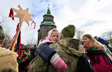 Украинский военнослужащий с дочкой на руках празднуют Рождество. В этом году Украина, в знак пренебрежения к России, впервые отпраздновала Рождество 25 декабря, а не 7 января, как это принято в православной церкви. Село Пирогово, окрестности Киева, 25 декабря. [Сергей Супинский/AFP]