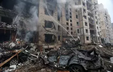 A firefighter extinguishes a fire in a multi-story building destroyed from a missile attack in the center of Kyiv, on January 2, amid the Russian invasion of Ukraine. [Anatolii Stepanov/AFP]