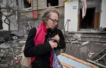 A local resident carries a cat as she walks out from a damaged residential building in the center of Kharkiv after a missile strike on January 2, amid the Russian invasion in Ukraine. Ukrainian President Volodymyr Zelenskyy denounced 'Russian terror' January 2 as fresh missile strikes on Kyiv and Kharkiv killed at least four people after Moscow intensified its campaign against Ukraine. [Sergey Bobok/AFP]