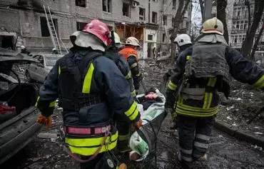 Ukrainian rescuers carry a wounded woman out of a damaged residential building in the center of Kharkiv after a missile strike on January 2, amid the Russian invasion in Ukraine. [Sergey Bobok/AFP]