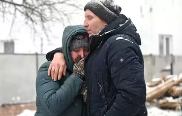 Local residents react next to a site hit by Russian strikes in Zmiiv, Kharkiv province, Ukraine, on January 8, amid the Russian invasion of Ukraine. At least three people have been killed and dozens injured in a fresh wave of Russian strikes across the country, regional officials said. [Sergey Bobok/AFP]