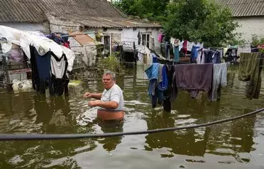 A local resident walks in the flooded yard of his house in Afanasiyivka, Mykolayiv province, on June 10, following the destruction of the Kakhovka hydroelectric dam. [Oleksii Filippov/AFP]