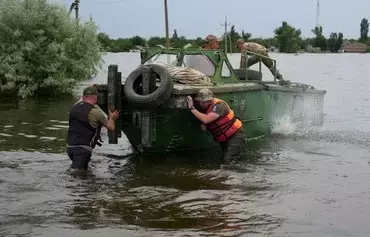 Спасатели толкают лодку во время эвакуации из района, затопленного после повреждения плотины Каховской ГЭС. Афанасьевка, Николаевская область, 10 июня 2023 г. [Алексей Филиппов/AFP]