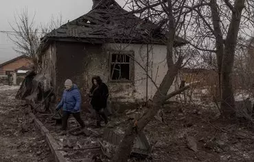 Local residents walk next to a heavily damaged house following Russian shelling in Kyiv, on December 11, amid the Russian invasion of Ukraine. [Roman Pilipey/AFP]