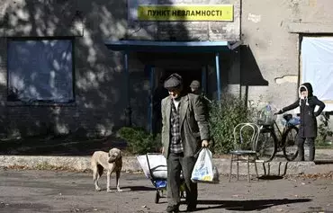 Local resident Anatolii, 84, walks in front of a heated 'invincibility point' where people can get food and recharge their devices in the frontline town of Chasiv Yar, in Donetsk province on October 11, amid the Russian invasion of Ukraine. [Genya Savilov/AFP]