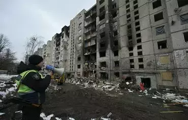 A policeman uses a loud speaker in front of a heavily damaged residential building, three days after a Russian missile attack in Kyiv, on January 5. [Genya Savilov/AFP]