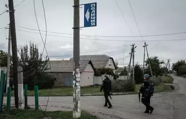 A blue Russian-language sign with the word 'police' is seen September 20, 2022, in Kozacha Lopan, Kharkiv province, after Ukrainian forces retook the town. The sign points to a police station that a local pro-Russian militia used as a base during the Russian occupation. [Yasuyoshi Chiba/AFP]