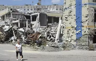 A woman walks past a destroyed building in Mariupol on August 16, 2023, amid the Russian invasion of Ukraine. [AFP]