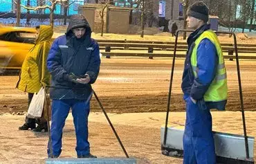 Uzbek migrant workers are shown clearing snow in Moscow last February 23. [File]