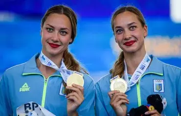 Ukrainian gold medalists Maryna Aleksiiva and Vladyslava Aleksiiva pose after competing in the Women's Artistic Swimming duet free final event on August 13, 2022, at the LEN European Aquatics Championships in Rome. [Filippo Monteforte/AFP]