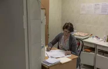 A doctor completes forms while receiving a pregnant woman in a maternity hospital of Pokrovsk, Donetsk province, on January 24, amid the Russian invasion of Ukraine. [Roman Pilipey/AFP]