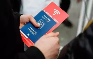 A Ukrainian refugee holds a passport and a flyer for mobile phone subscriber identity module cards at the main railway station in Dresden, Germany, on March 22, 2022. [Jens Schlueter/AFP]