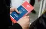 
A Ukrainian refugee holds a passport and a flyer for mobile phone subscriber identity module cards at the main railway station in Dresden, Germany, on March 22, 2022. [Jens Schlueter/AFP]        