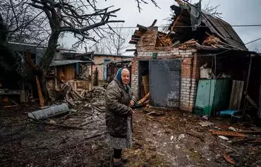 Пожилая женщина стоит на заднем дворе после обстрела в Часовом Яре, недалеко от Бахмута, 28 февраля 2023 г. [Димитар Дилкофф/AFP]