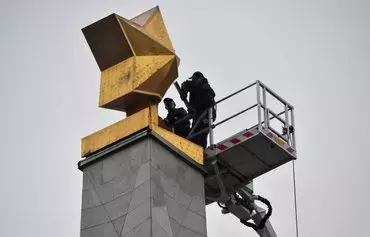 Workers dismantle a golden star from the Soviet-era World War II memorial obelisk of the Hero City monument in Kyiv on November 4. [Sergei Supinsky/AFP]