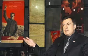 Then-Georgian President Mikheil Saakashvili gestures on February 25, 2009, near a poster of Soviet strongman Josef Stalin at the Soviet Occupation Museum in Tbilisi. [Irakli Gedenidze/AFP]