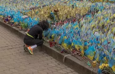 A woman reacts next to flags bearing symbols and colors of Ukraine set to commemorate fallen Ukrainian soldiers in Kyiv, on February 24, the second anniversary of Russia's invasion of Ukraine. [Roman Pilipey/AFP]