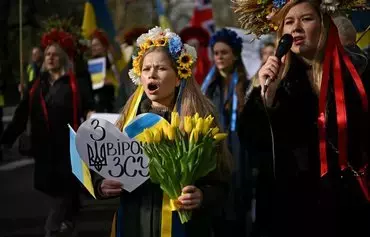 Demonstrators holding placards and Ukrainian flags take part in a solidarity march in London on February 24, to mark two years since the beginning of Russia's invasion of Ukraine. [Ben Stansall/AFP]