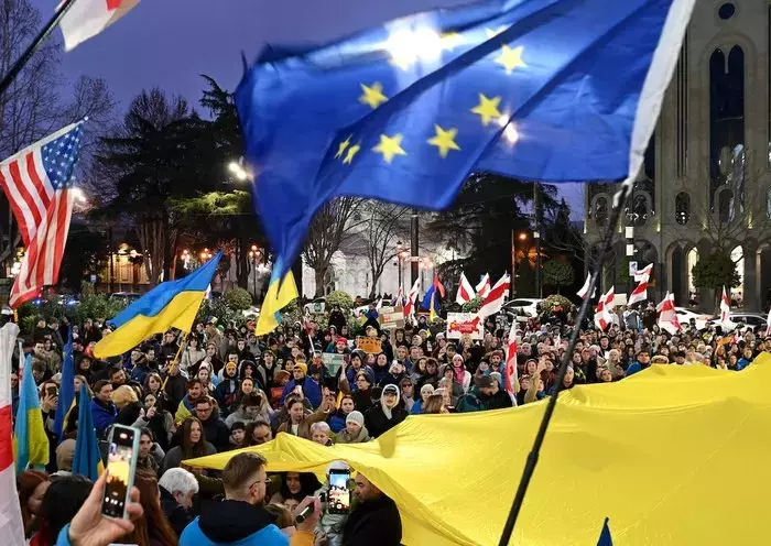 Demonstrators hold flags of Ukraine, the European Union and the United States as they parade through Tbilisi on February 24, to mark the second anniversary of the Russian invasion of Ukraine. [Vano Shlamov/AFP]