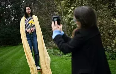 Photographer Vlada Stoliarova takes pictures of Ukrainian refugee Yulia Zabrodska while she poses in her garden in Blackheath, south London, on February 22. The photos are part of a series called 'Nezlamna' ('Unbreakable'), portraying Ukrainian female refugees who came to England amid the war in Ukraine. [Ben Stansall/AFP]