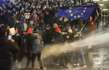 Protesters brandishing a European Union flag brace under spray from a water cannon during clashes with riot police near the Georgian parliament in Tbilisi last March 7. Georgian police used tear gas and water cannons against protesters who took to the streets in Tbilisi to oppose a controversial 'foreign agents' bill. [AFP]