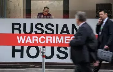 People walk past the 'Russian Warcrimes House,' which hosted a photographic exhibition documenting alleged war crimes committed by Russian troops in Ukraine, organised by The Victor Pinchuk Foundation, during the World Economic Forum (WEF) annual meeting in Davos on May 25, 2022. [Fabrice Coffrini/AFP]