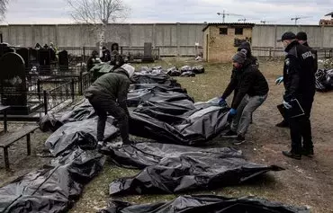 Workers line up bodies for identification by forensic personnel and police officers in the cemetery in Bucha, Ukraine, north of Kyiv, on April 6, 2022, after hundreds of civilians were found dead in areas from which Russian troops have withdrawn around the Ukrainian capital, including the town of Bucha. [Ronaldo Schemidt/AFP]