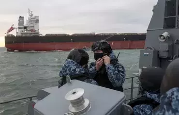 A Ukrainian Maritime Guard serviceman adjusts his helmet during the inspection of a cargo ship for prohibited items and substances before entering a port in the northwestern part of the Black Sea, on December 18, amid the Russian invasion of Ukraine. [Anatolii Stepanov/AFP]