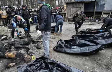 Policemen and city workers transfer six partially burnt bodies into body bags as reporters attend in the town of Bucha, Ukraine, on April 5, 2022, as Ukrainian officials say they had recovered more than 400 civilian bodies from the wider Kyiv region, many of which were buried in mass graves. [Genya Savilov/AFP]