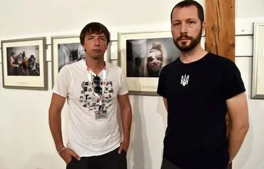 Ukrainian photographers Evgeniy Maloletka (left) and Mstyslav Chernov (right) pose in front of their photos at the 'Mariupol, Ukraine' exhibition in Perpignan, France, on August 31, 2022. [Raymond Roig/AFP]