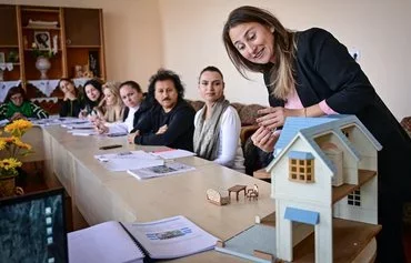 A Romanian woman repeats the names of the parts of a toy house to language teacher Sorina Stoianova (unseen) during the free weekly Romanian language lesson at the kindergarten in Vulcanesti, Gagauzia, Moldova, on November 14. [Daniel Mihailescu/AFP)