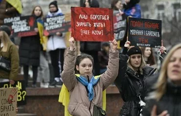 Women hold signs reading 'Only through fighting can one survive' and 'Captivity kills, and so do silence and indifference' as relatives and friends of Ukrainian prisoners of war rally in front of the Kyiv Opera on March 17, calling for their exchange with Russian prisoners, amid the Russian invasion of Ukraine. [Genya Savilov/AFP]