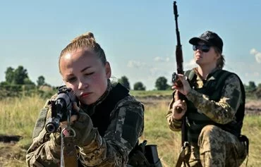 Female Ukrainian cadets, wearing new military uniforms designed specially for women, take part in training during an event called 'The uniform matters,' which the army organized to present the outfit and test it under military training conditions, on the outskirts of Kyiv on July 12. [Sergei Supinsky/AFP]